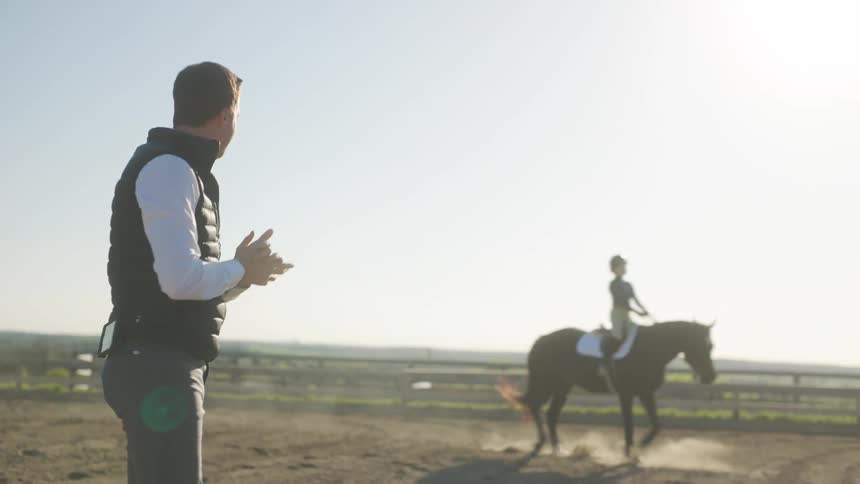 Horse riding instructor watching a woman riding a horse in a farm