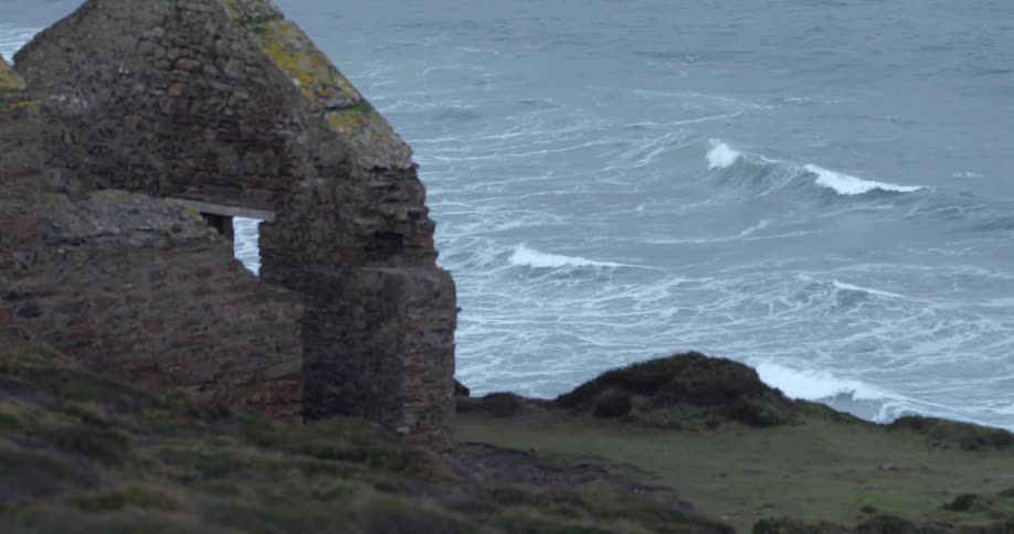 Old building ruins on coast with waves rolling in