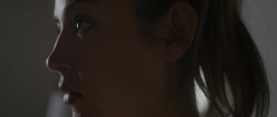 A woman with lipstick in a room staring off into the distance