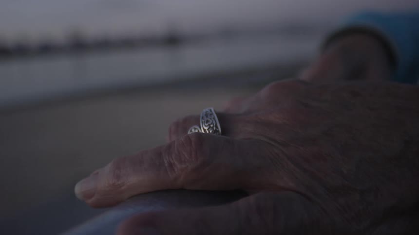 Close up of elderly hands resting on a handrail outside