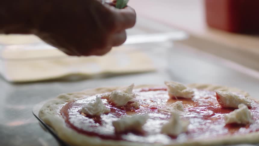 A woman prepares a pizza at a restaurant