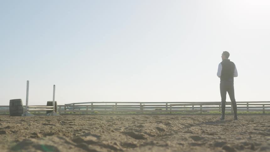 A man training a girl on equestrianism in a corral at the ranch