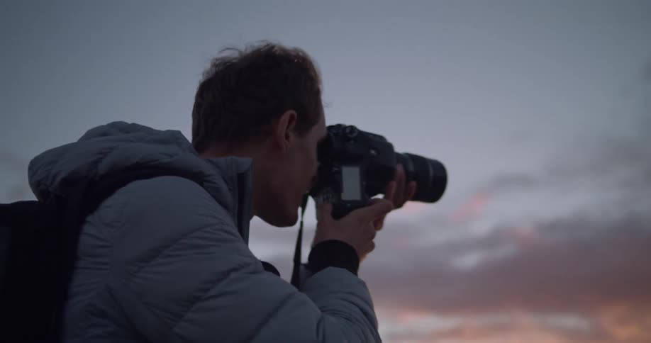 A photographer taking a picture of the sunset over the ocean