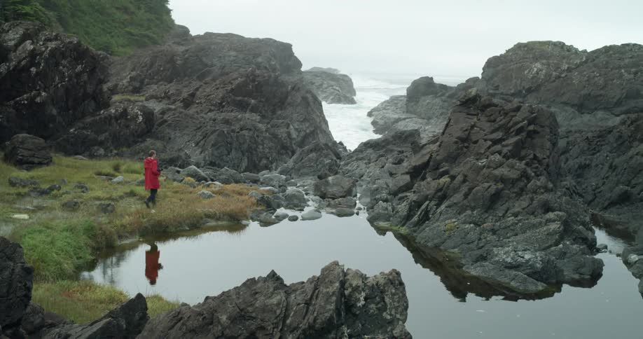A man carrying a camera walks to the water to take photos