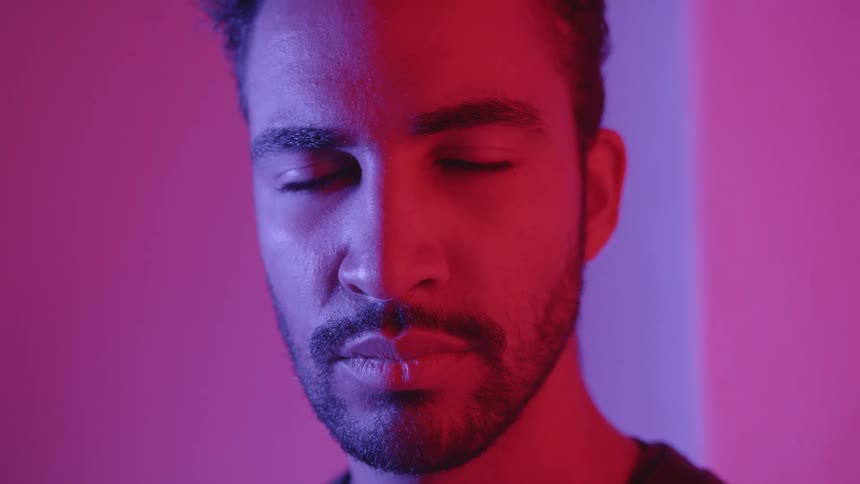 A man standing in a room with his eyes close then opening his eyes