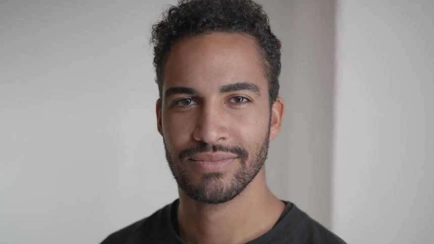 A man is standing indoors and smiling