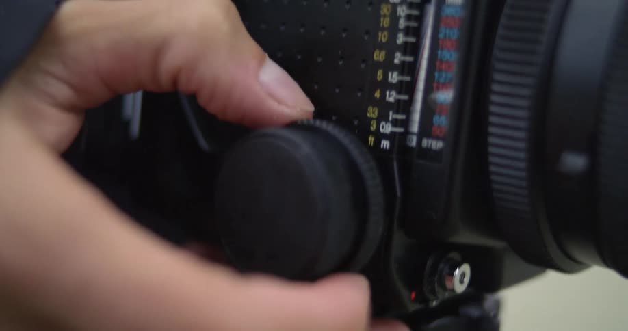 Close up of a photographer adjusting the dials and controls of a film camera