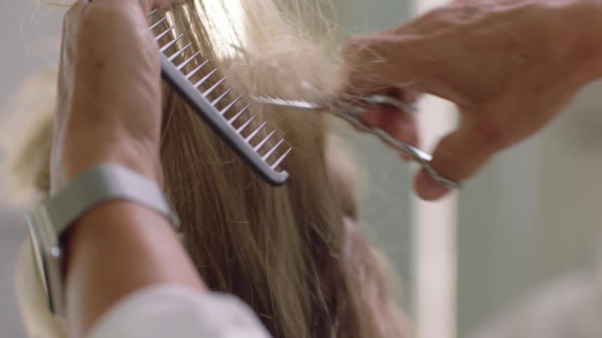 A males hairdresser cuts a hair with scissors and a comb