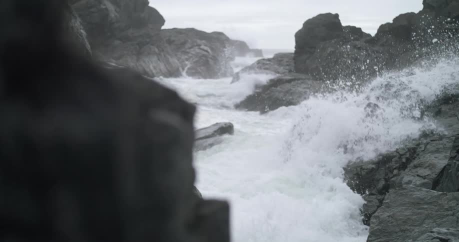 Water splashing as it crashes into a rocky coastline on a cloudy day