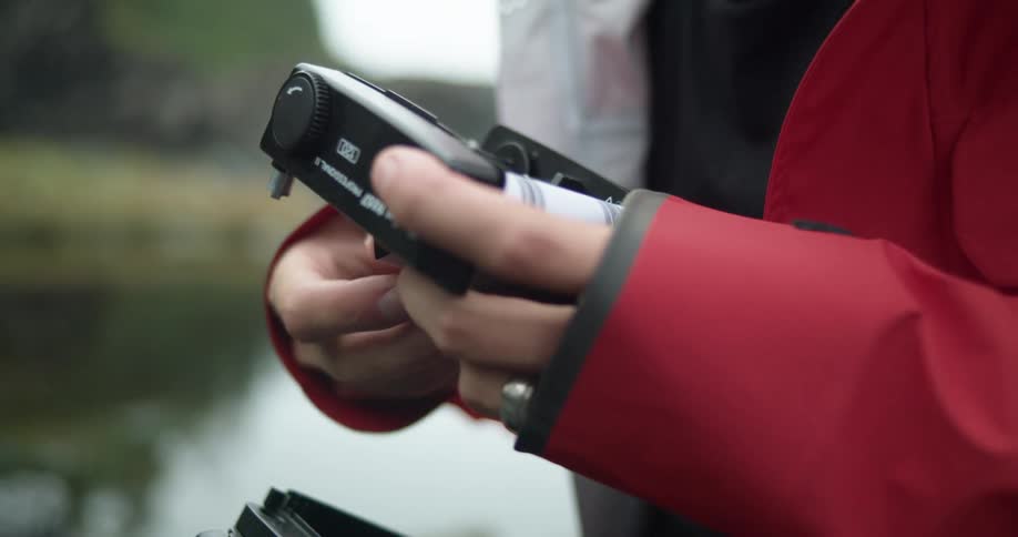 A person loads film into their camera outdoors