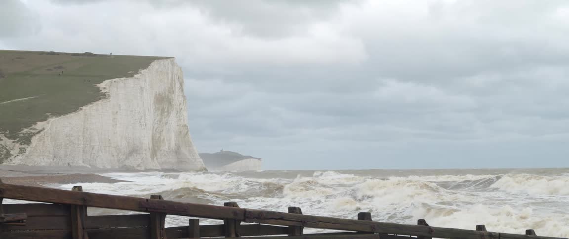 Ocean waves crash against the shore with cliff in the background