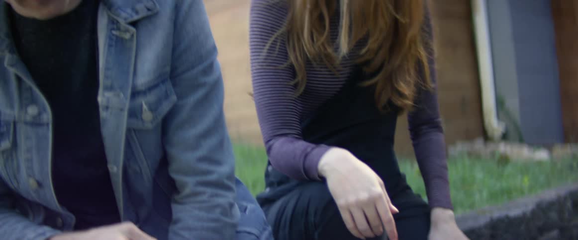 A man and woman are sitting outdoors in their backyard