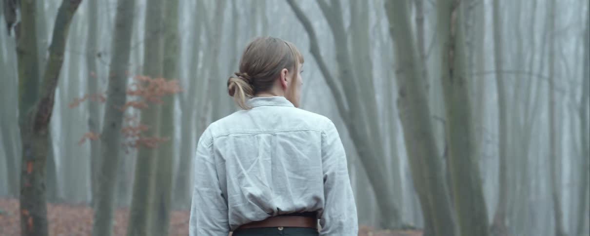 Woman wandering alone in the middle of a misty forest