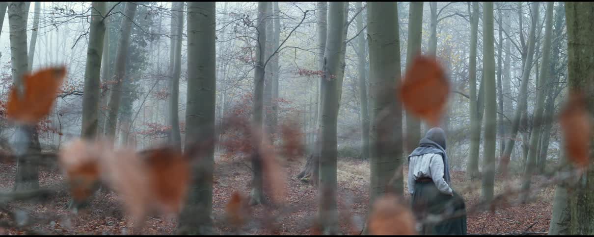 A woman is hiking through the foggy forest