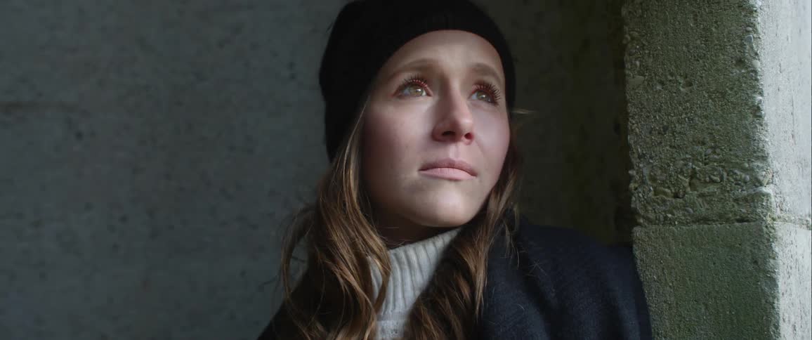 A woman in a winter hat and coat looking around