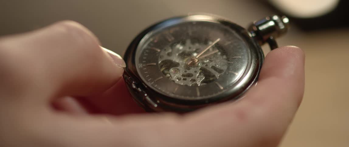 A person is holding a watch indoors
