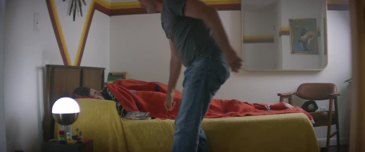 Father reads a book to child in bed