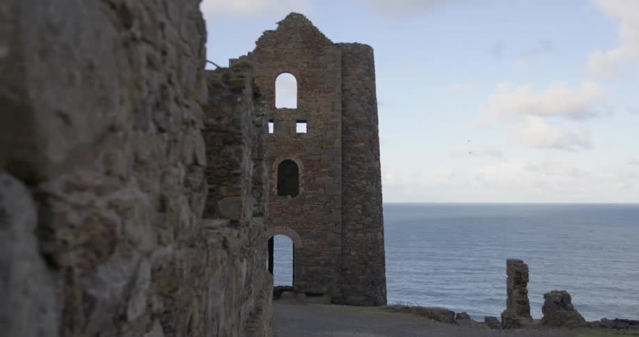 A ruin made of stone against a body of water and a blue sky
