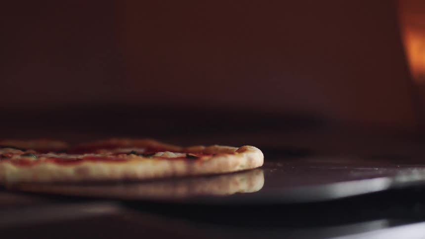 A pizza being put into a fire oven