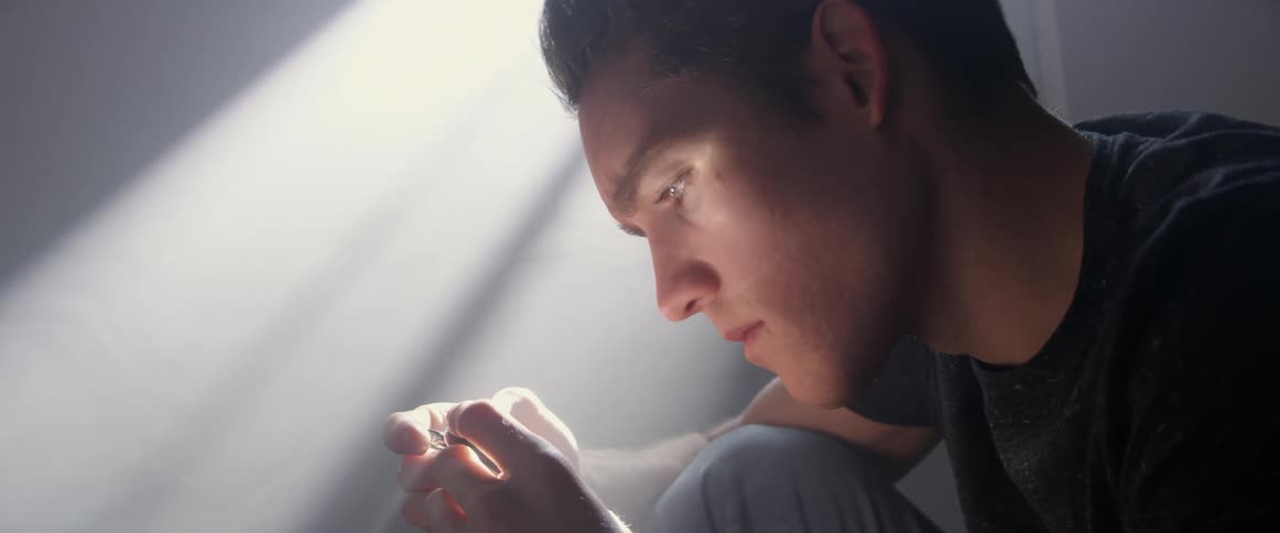 A man is sitting down in a room during the day