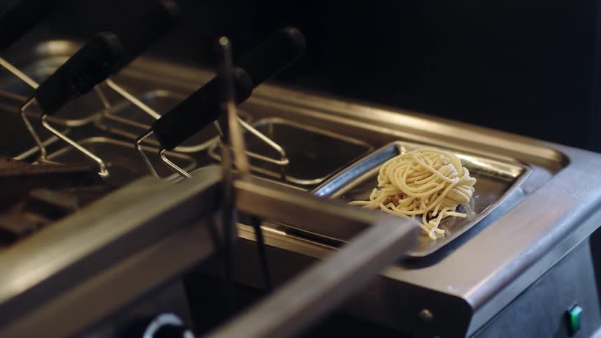 A portion size of spaghetti on a tray next to a stove