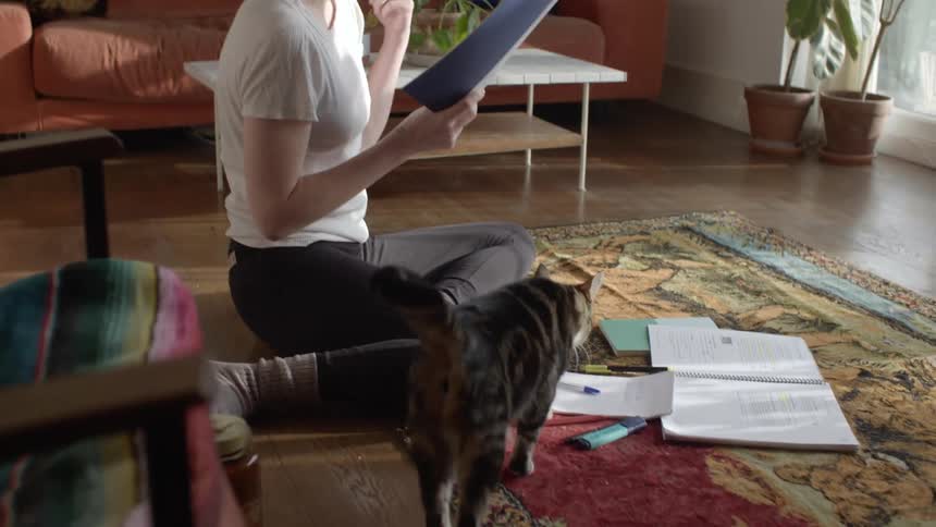 A woman is sitting in a house and reading papers