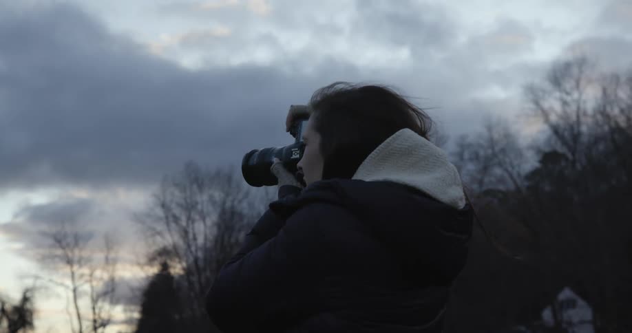 White woman taking pictures of the nature on a professional camera