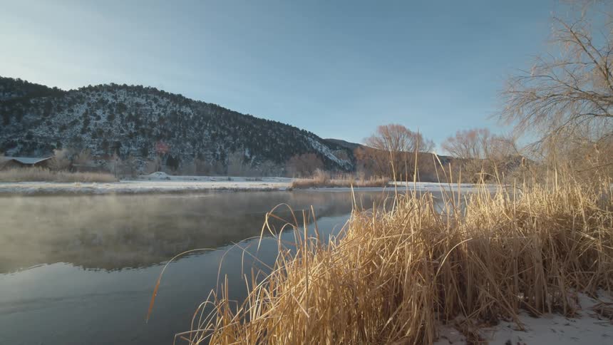 A river with snow and tree covered hills on the bank