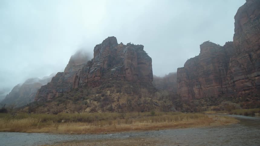A stream running along rocky mountains with fog