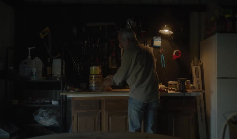 Man puts a bag of seeds over a table inside a dimly lit room