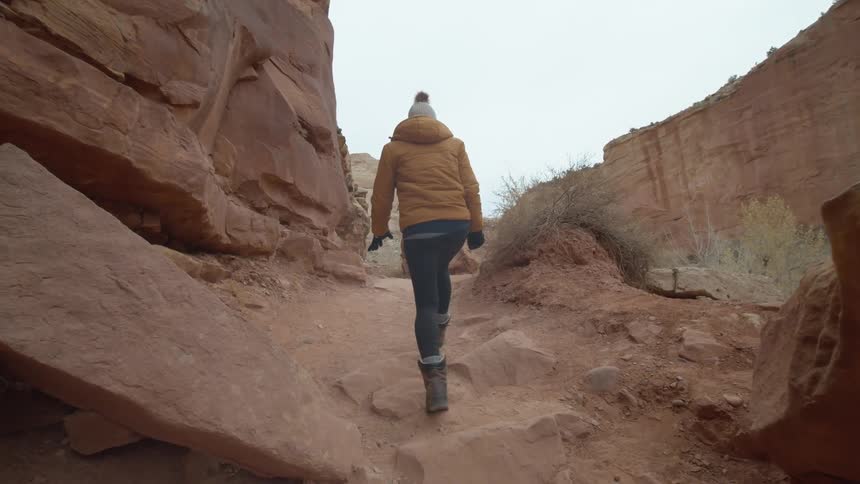 Woman wearing winter clothing walking in a canyon alone