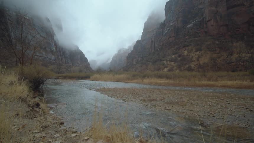 Clouds hanging over the peaks of a canyon with a river flowing through