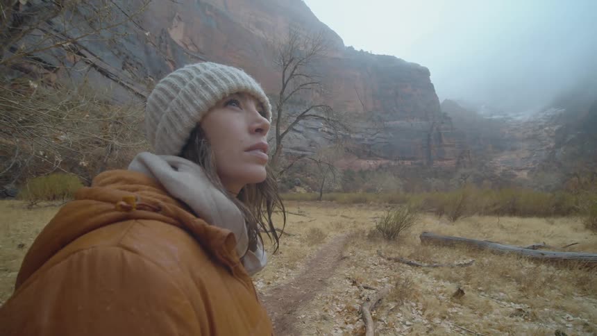 Young woman lookin at the sky standing on a trail through the mountains