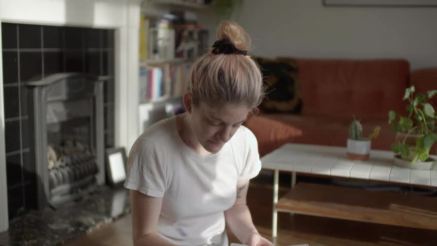Young woman sittin gon the floor of the livingroom studying a lesson