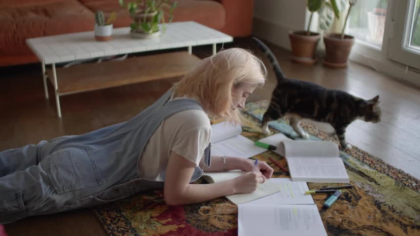 A woman is studying on the floor of her house