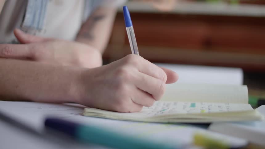 A person writing and highlighting in a notebook