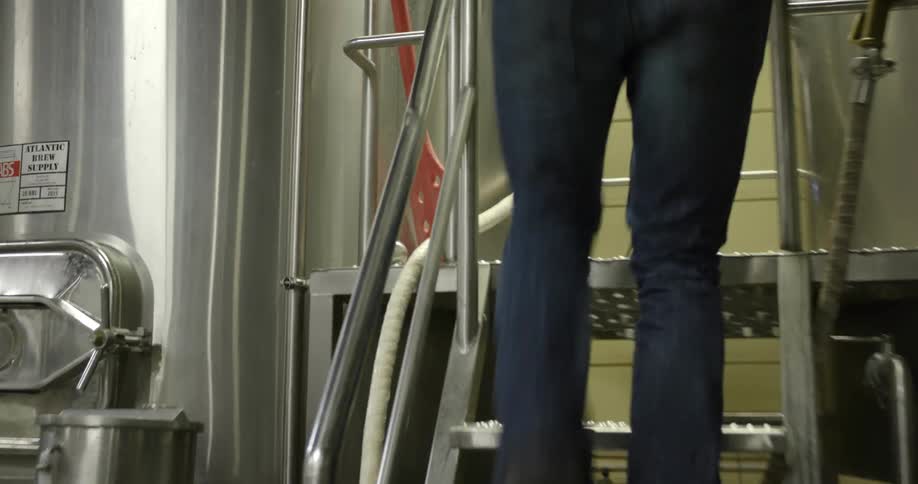 A man walks up metal stairs to a large metal container