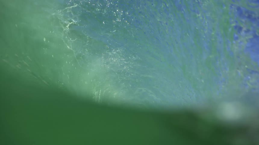 A large waves crashes onto turquoise ocean water