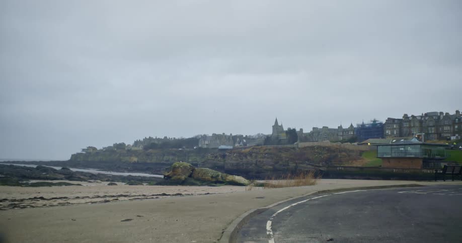 A road next to the sand of a beach close to a town at daytime