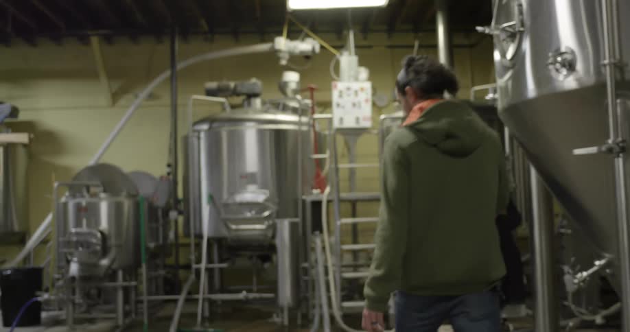 An employee in a factory walks towards a row of large metal tubs