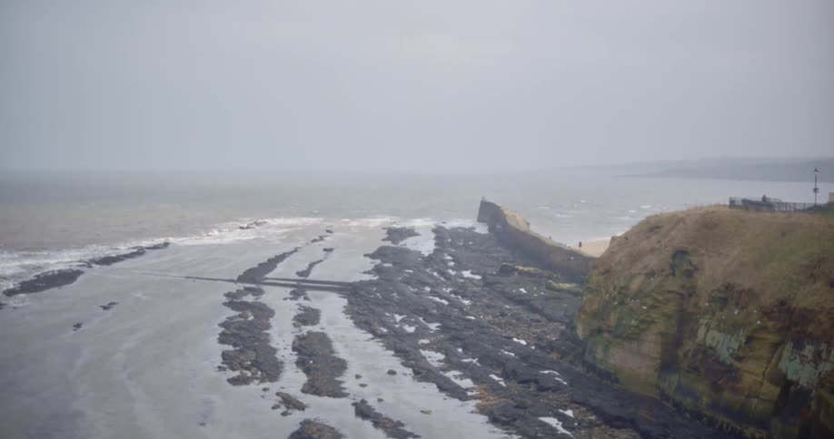 The waves crash against the shore on a cloudy day