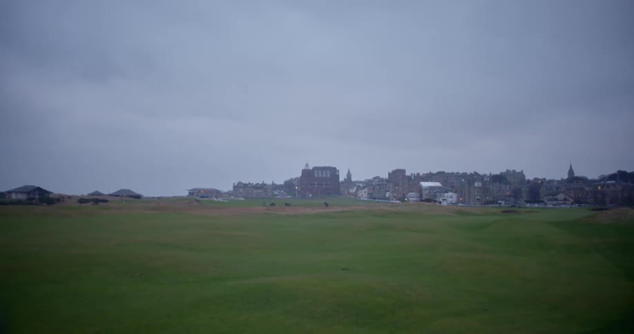 Landscape of overcast sky grassy field and a small town