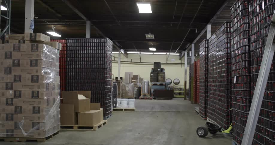 Cardboard boxes and plastic packaging are piled high on pallets in a factory