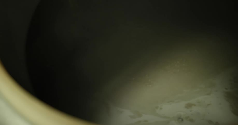 Water drips from a faucet into a tall narrow tub