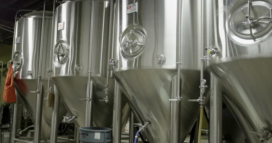Shiny metallic stainless steel fermenting vats inside a distillery