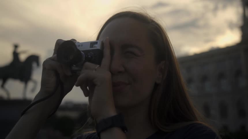 A woman takes a photo with a vintage camera