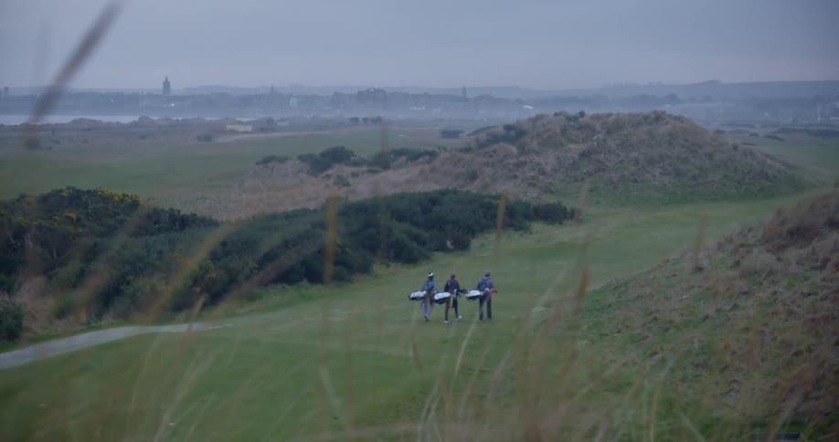 Three golf players carry their gags on the course