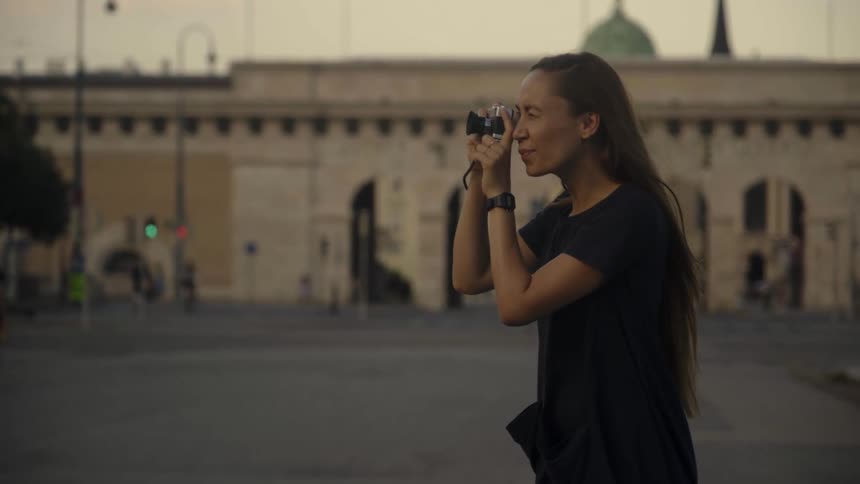 A woman is taking pictures in a city