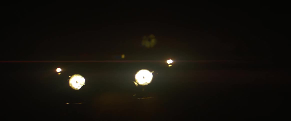 The vehicle has bright headlights shining at night