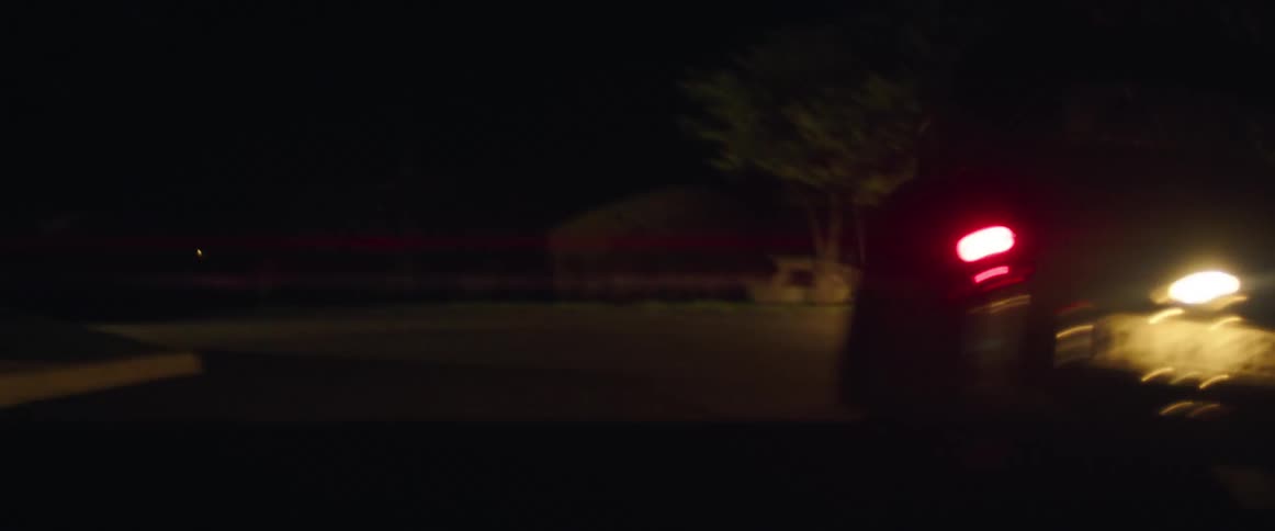 A black car taking a sharp turn while driving at night